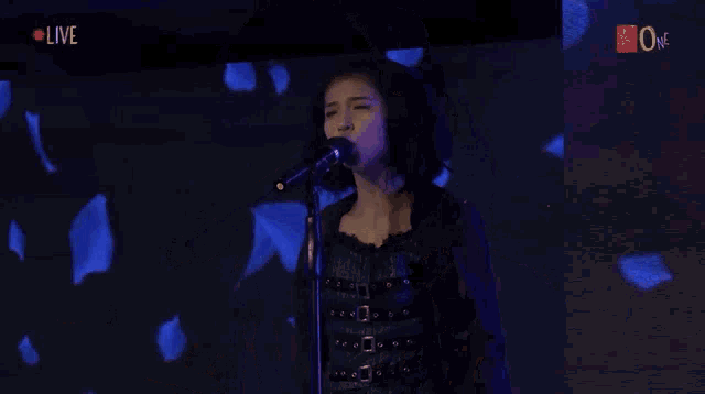 a woman singing into a microphone with the word live on the screen
