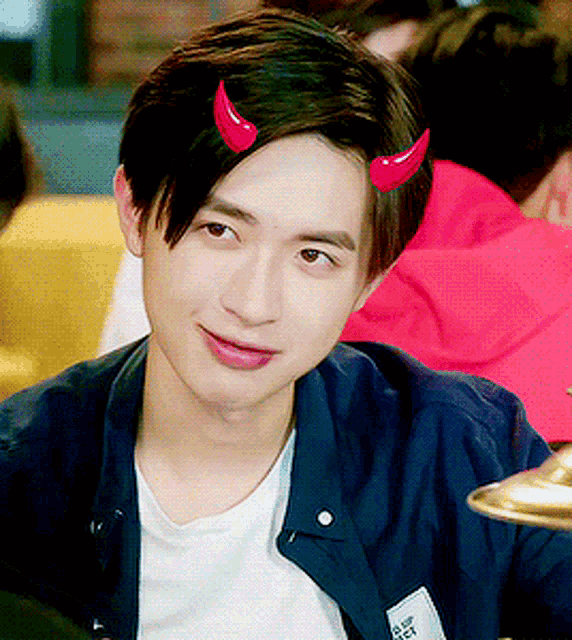 a young man with devil horns on his head is wearing a white shirt