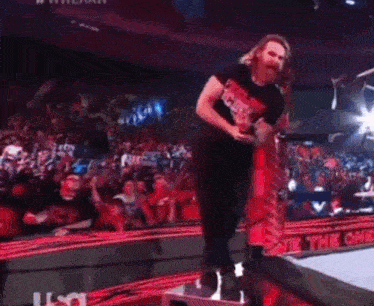 a wrestler wearing a shirt that says ucky is standing in a ring