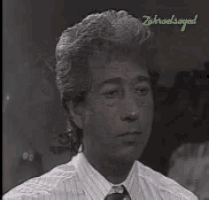 a man in a striped shirt and tie is looking at the camera with a caption that says ' zikreelsaged '