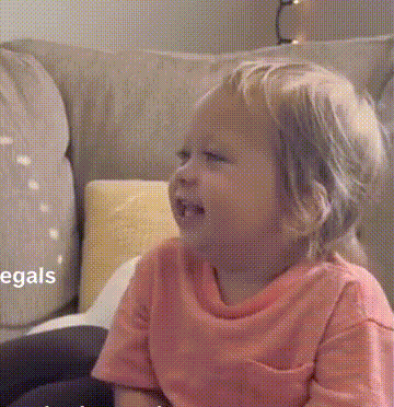 a little girl is sitting on a couch and crying .