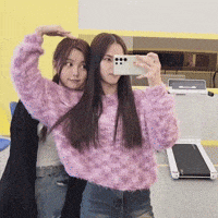 two girls are taking a picture of themselves with their cell phones