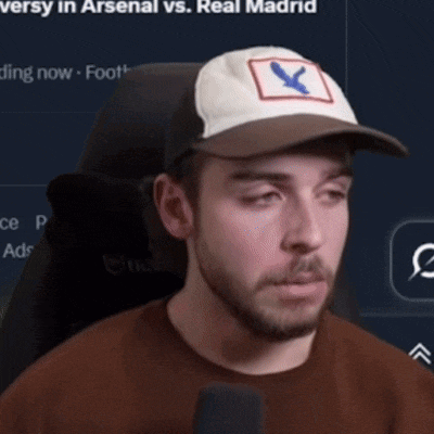 a man wearing a baseball cap with a bird on it is talking into a microphone