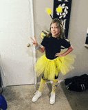 a little girl dressed in a bee costume is standing in a room .