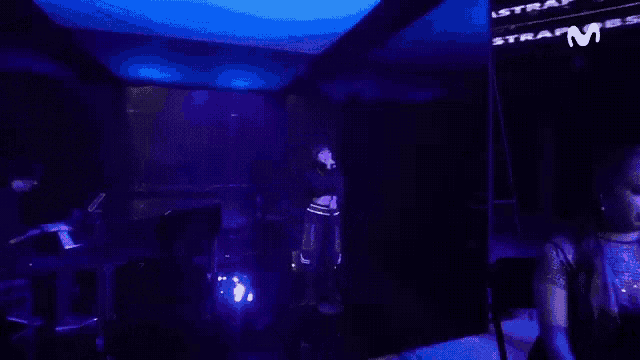 a woman is singing into a microphone on stage in a dark room .