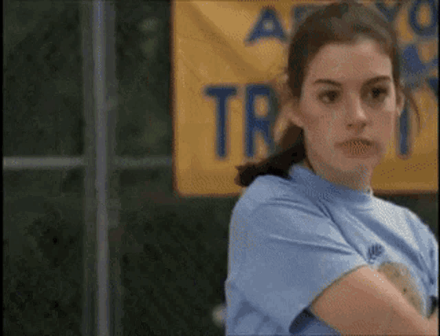 a woman in a blue nike shirt stands in front of a yellow sign that says a.
