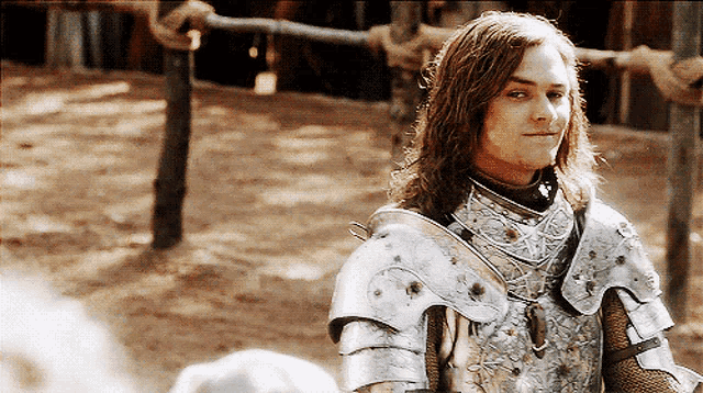 a man with long hair is wearing armor and looking at something