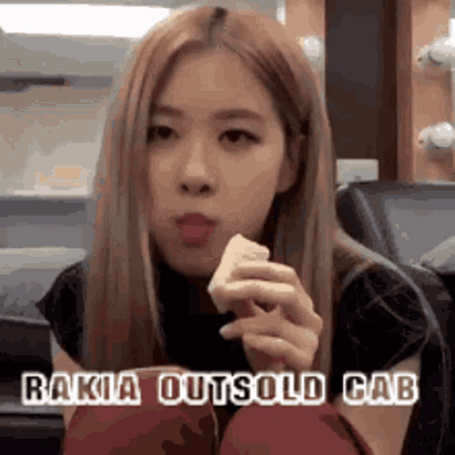 a woman is eating a piece of food with the words rakia outsold cab written above her .