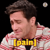 a man in a striped shirt is making a face and saying pain .