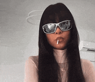 a woman with long hair wearing sunglasses and a cigarette in her mouth