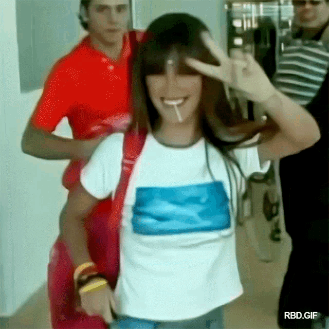 a girl with a cigarette in her mouth is giving a peace sign