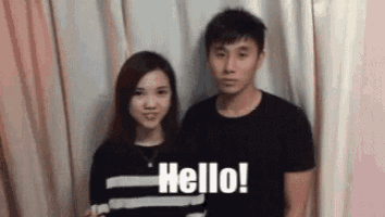 a man and a woman are standing next to each other in front of a pink curtain .