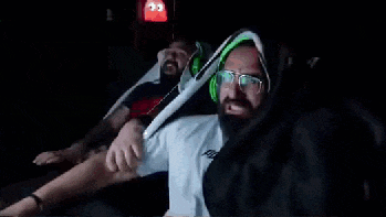 a man with a beard and green headphones is playing a video game in a dark room .
