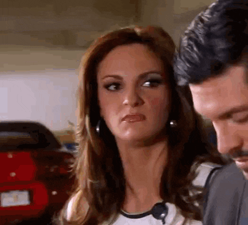 a man and a woman are standing next to each other and the woman is making a funny face .