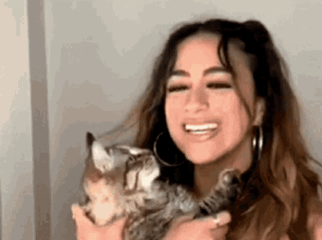 a woman is holding a cat and smiling .