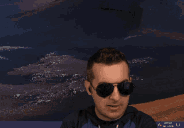 a man wearing sunglasses and a blue shirt holds his fist up in the air