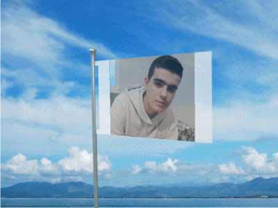 a flag with a picture of a young man on it against a blue sky