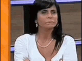 a woman is sitting with her arms crossed and looking at the camera .