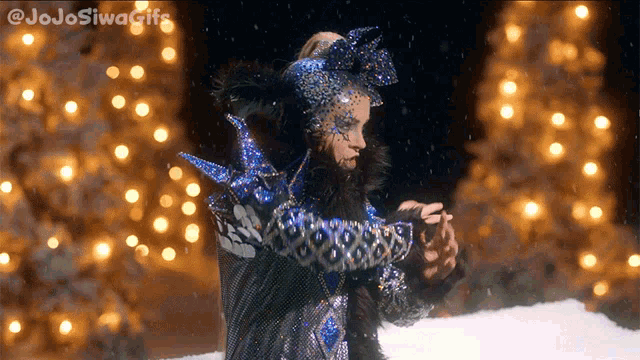 a woman in a fancy costume is standing in front of a christmas tree with the hashtag jojosiwagifs