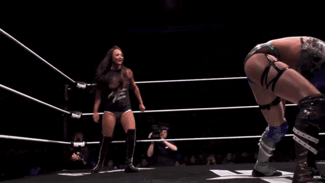 two wrestlers are wrestling in a ring with a referee watching