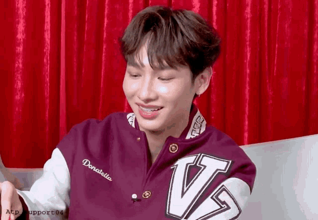 a young man wearing a purple and white jacket with the letter v on it