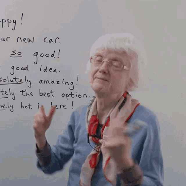 an elderly woman stands in front of a whiteboard that says " happy "