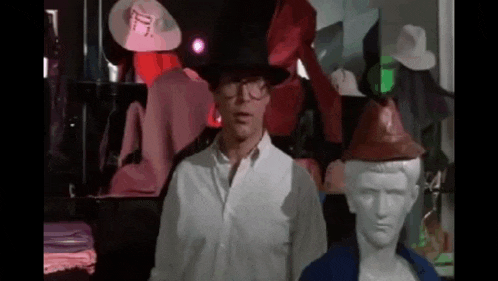 a man wearing a top hat and glasses is standing in front of a mannequin .