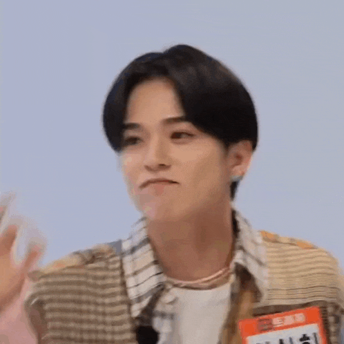 a young man is waving his hand and making a funny face while wearing a name tag .