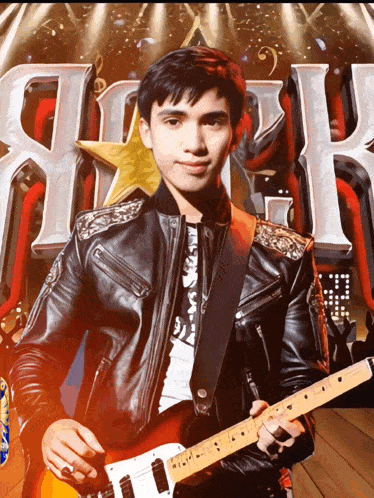 a young man in a leather jacket is playing a guitar in front of a sign that says rock