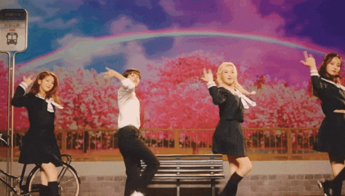 a group of girls in school uniforms are dancing in front of a bus stop