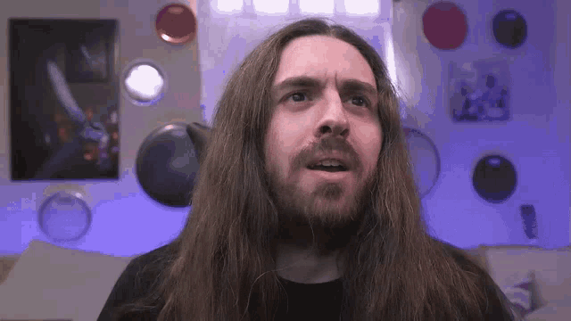 a man with long hair and a beard is making a funny face in a room .