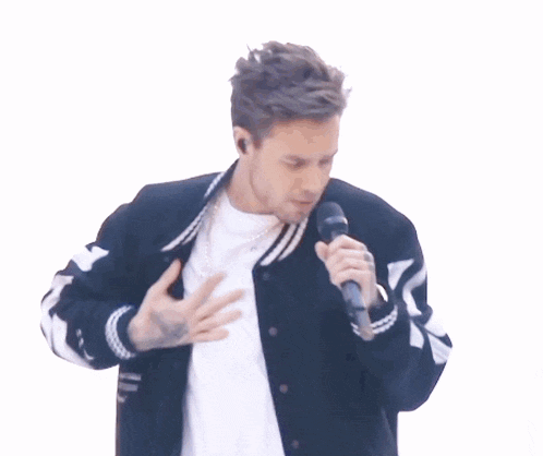 a man singing into a microphone with a black and white jacket on