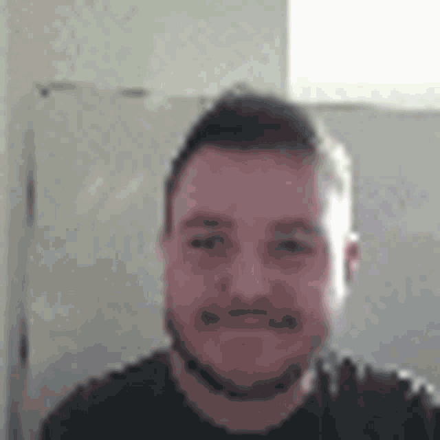 a man with a beard is taking a selfie in front of a window .