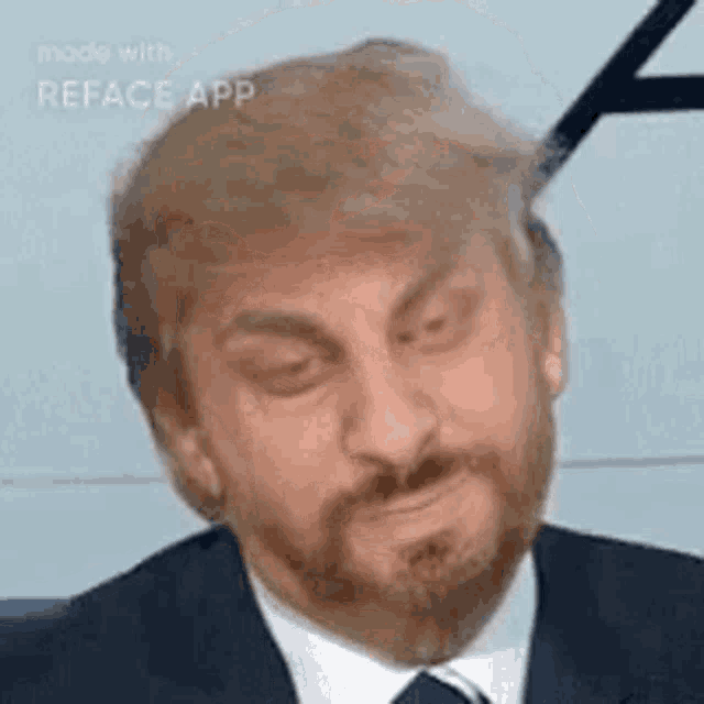 a man in a suit and tie with a beard is being cut off his hair with scissors .