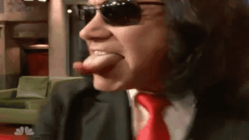 a man wearing sunglasses and a red tie sticking out his tongue