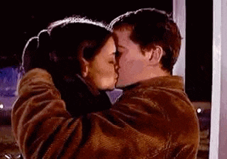 a man and a woman are kissing each other in front of a window .