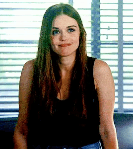 a woman with long hair is sitting in front of a window and smiling .