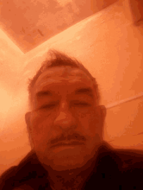 a man with a mustache takes a selfie with his eyes closed