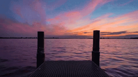 a dock overlooking a body of water with a sunset sky in the background