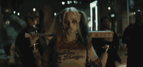 harley quinn is blowing a bubble while holding a bat in her hand .