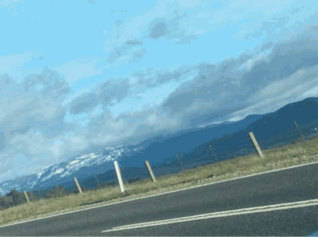 a road with mountains in the background and a fence along the side