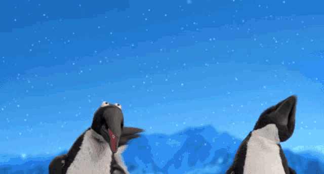 a group of penguins are standing in the snow with mountains in the background