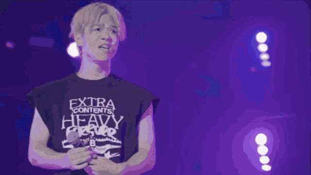 a man singing into a microphone with a shirt that says extra contents