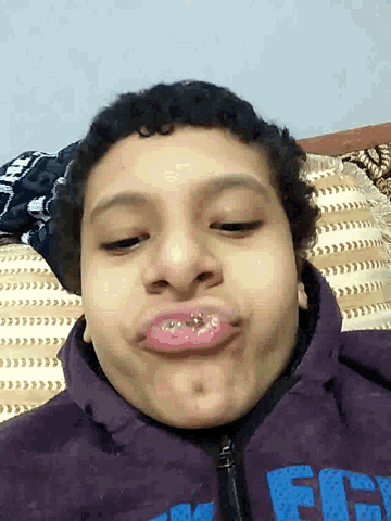 a boy wearing a purple jacket with the word fifty on it makes a funny face