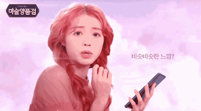 a woman with red hair is holding a cell phone in front of a sign that says ' korean ' on it