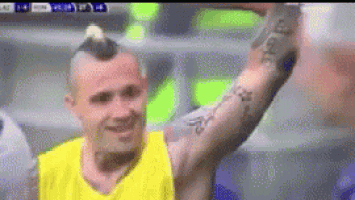 a man with a tattoo on his arm is wearing a yellow shirt and smiling