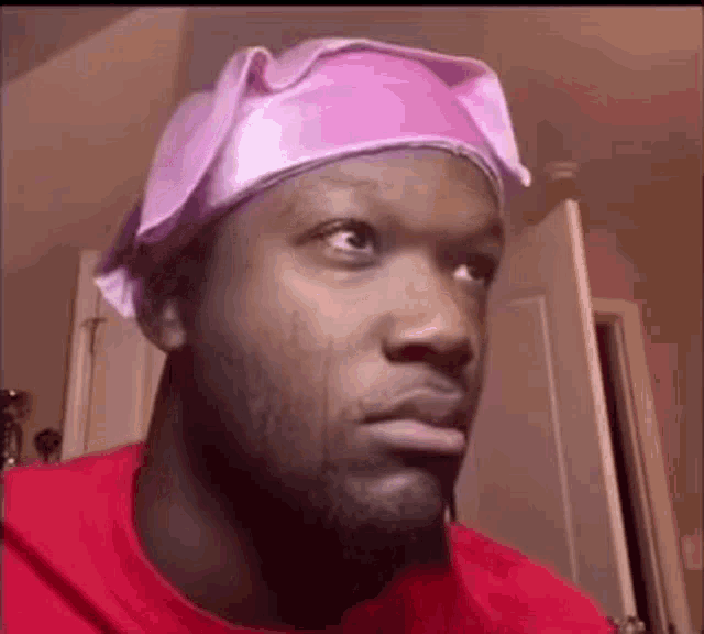 a man wearing a pink hat is looking at the camera .