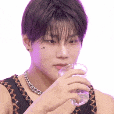 a young man with a tattoo on his face drinks from a cup