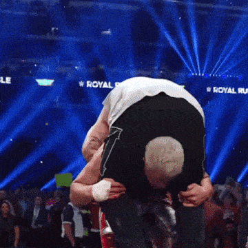 a wrestler is carrying another wrestler over a rope