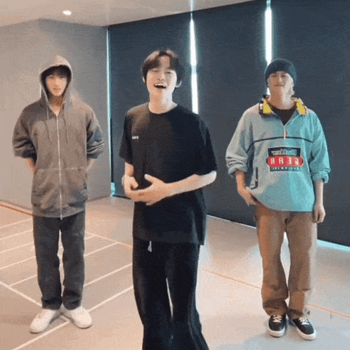 three young men are standing in a room and one of them is wearing a jacket that says ' a38 ' on it
